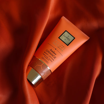 La PIEL Amber Orange Body Lotion Tube On Orange Fabric
